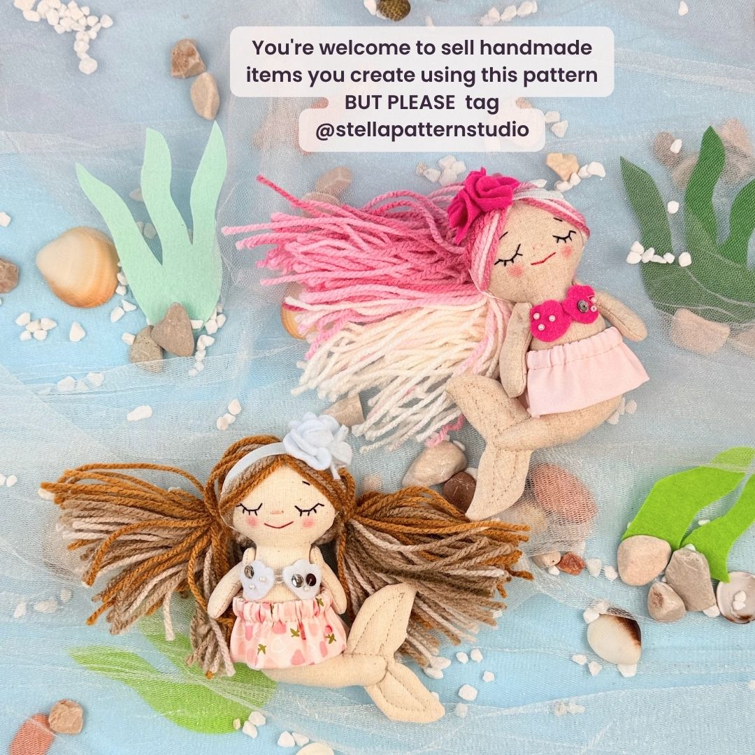 Two handmade dolls with yarn hair on a beach-themed background with shells and plants.